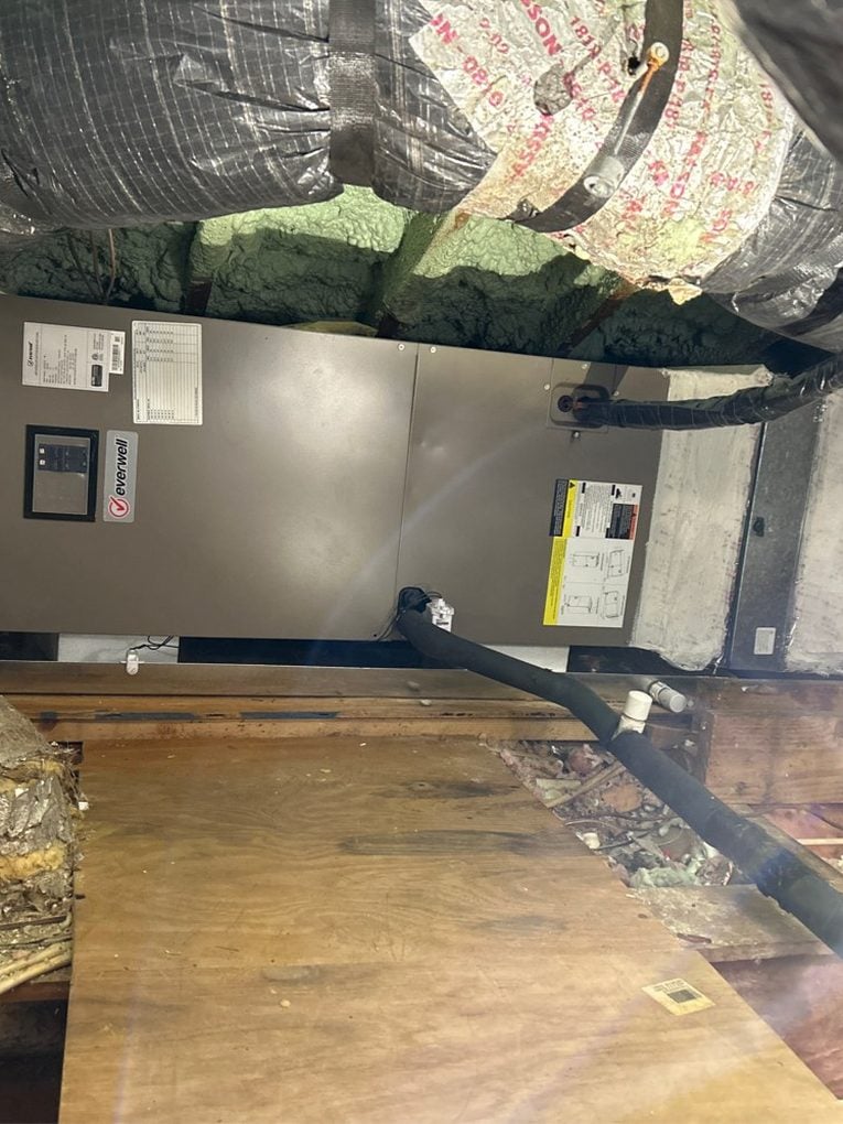 An air handler installed in a Jacksonville attic with insulated flex ducts reconnected and the condensate line run out across the decking