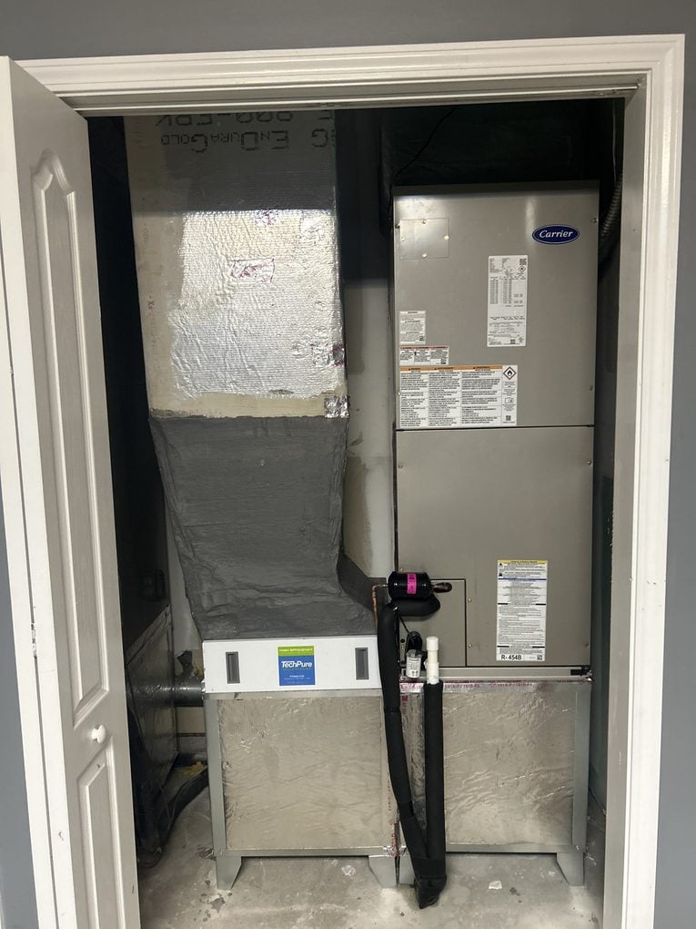 A Carrier air handler installed in an indoor closet with a high-efficiency media filter and an insulated return plenum
