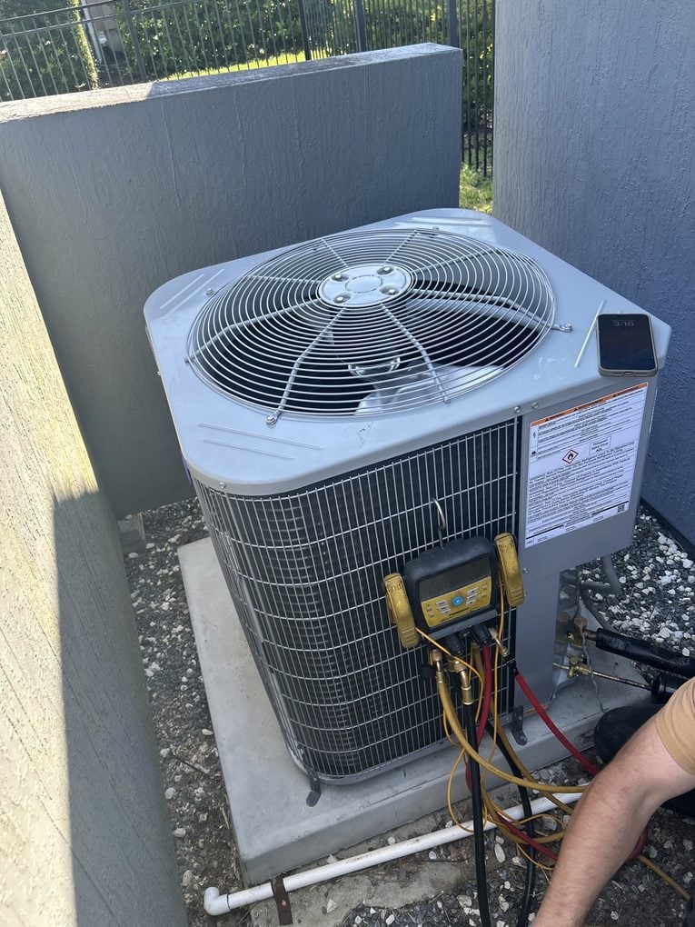 A Great Dane technician checking refrigerant pressures with manifold gauges on a newly installed Carrier condenser